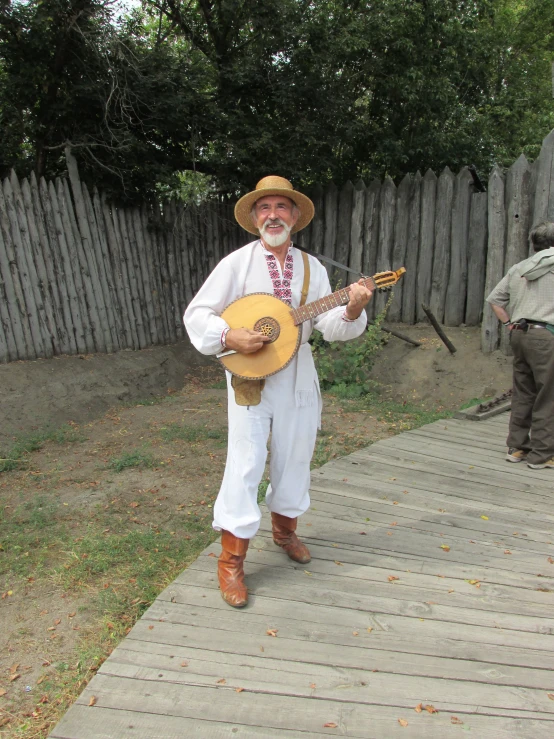 a man is playing on a wooden guitar outside