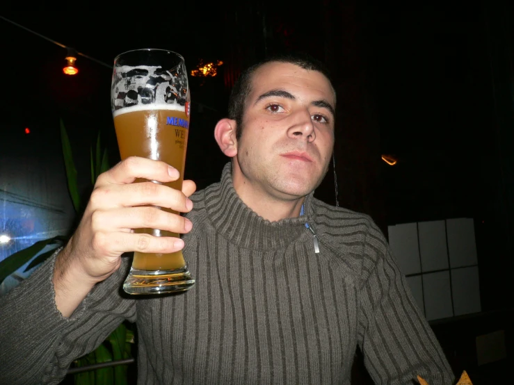 a man holding a beer glass and looking at the camera