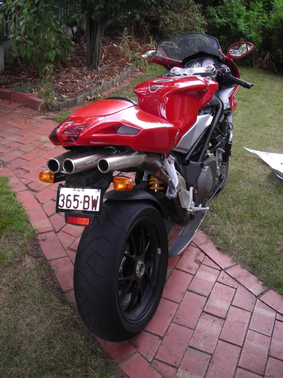 a red motorcycle parked on top of a brick road