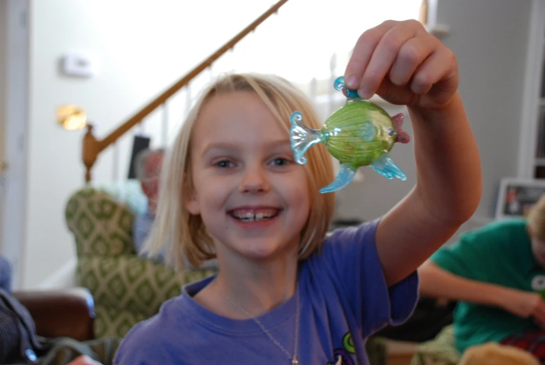 the  is holding up her green fish toy