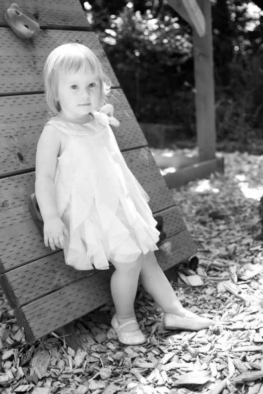 a little girl posing for the camera while wearing her dress and sandals