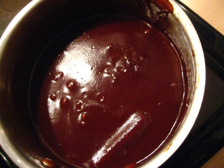 a sauce pot filled with red sauce on top of a stove