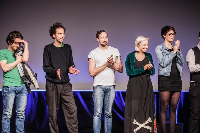 people at a screen with hands folded and one standing behind a woman