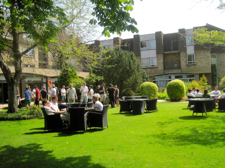 an outdoor lawn with many people at tables and chairs