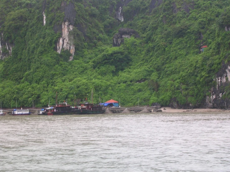 many small boats are docked in front of tall green mountains