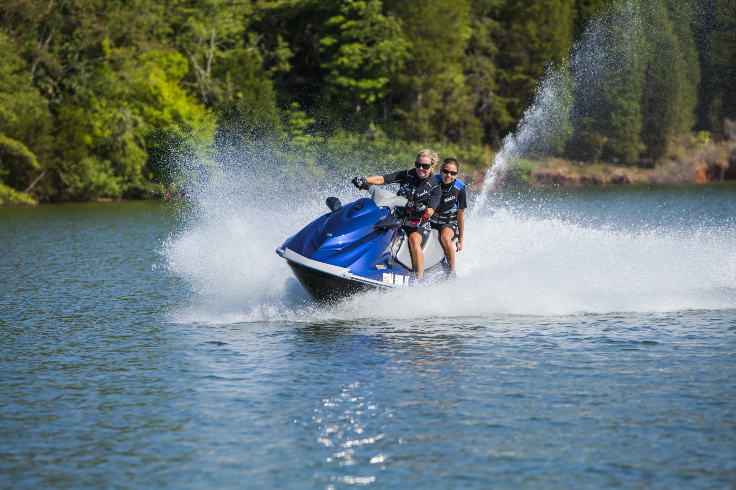 a man and woman riding on the back of a blue jet ski