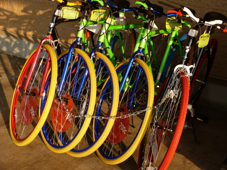 a row of bicycles that are brightly colored and have red spokes