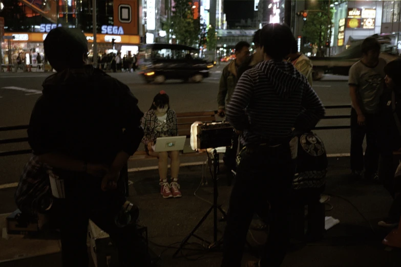 people gather on the sidewalk at night in the city