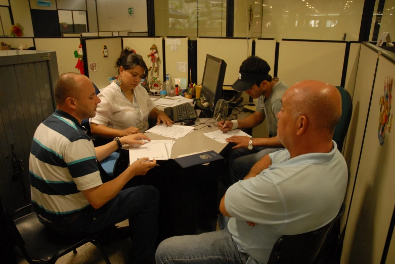 people sitting around a table and one man is signing documents