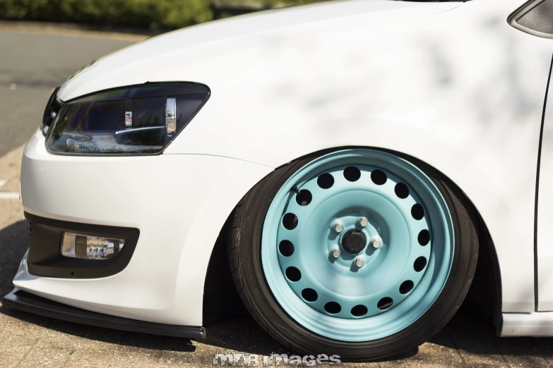 a close up of the front of a white car with a blue tire