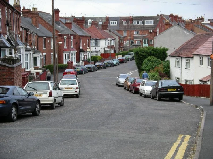 a road lined with parked cars is shown in this suburban area
