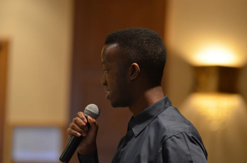 man with microphone up to his ear standing in front of a light