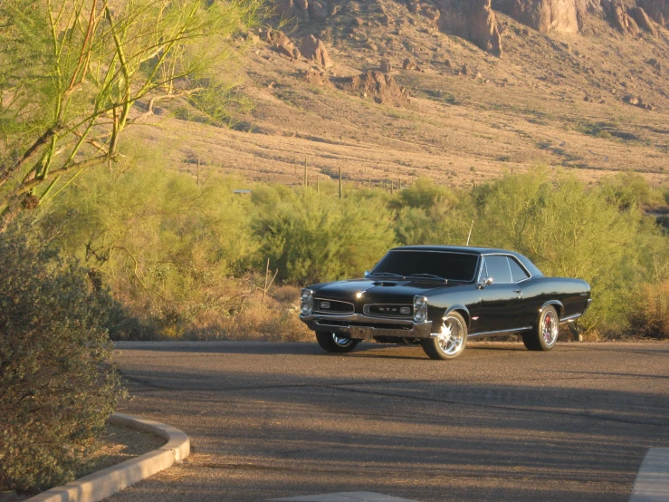 an old black car parked in the middle of the road