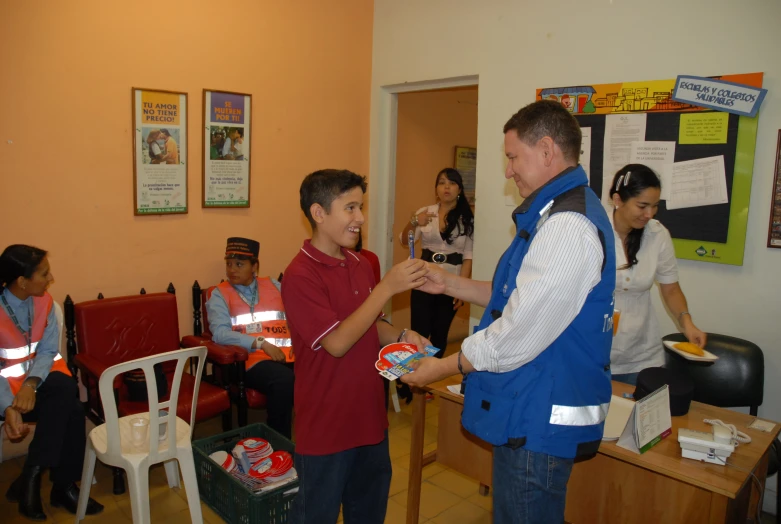 a young man is standing with his hand in a room with people