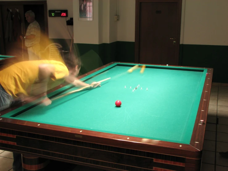 a man is leaning over the edge of a pool table