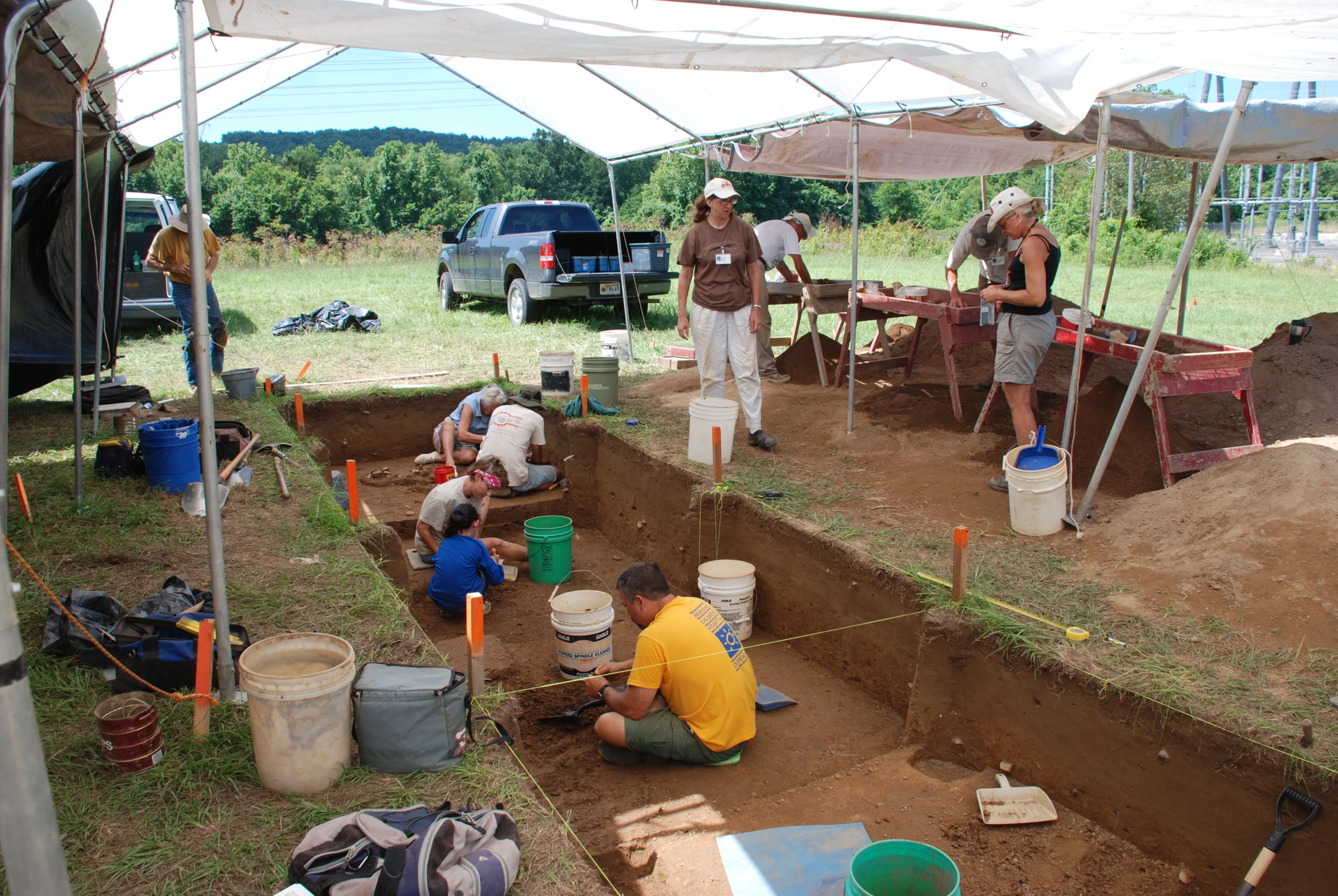 people are digging for a foundation under a canopy