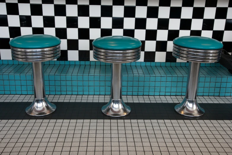 the modern look of an diner with two stools and blue tiled wall