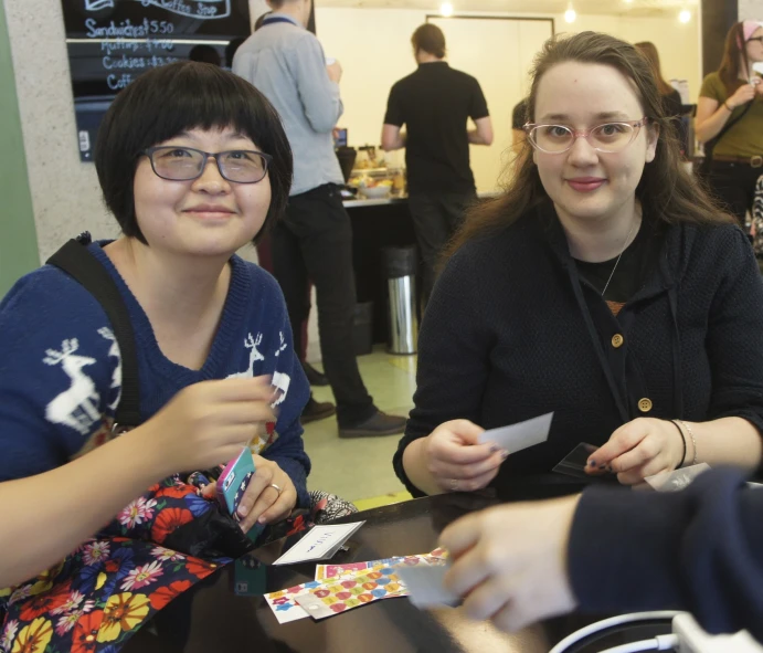 two girls smile as they sit at a table