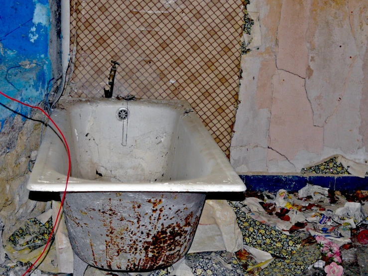 an old bath tub with a hole in the wall next to it