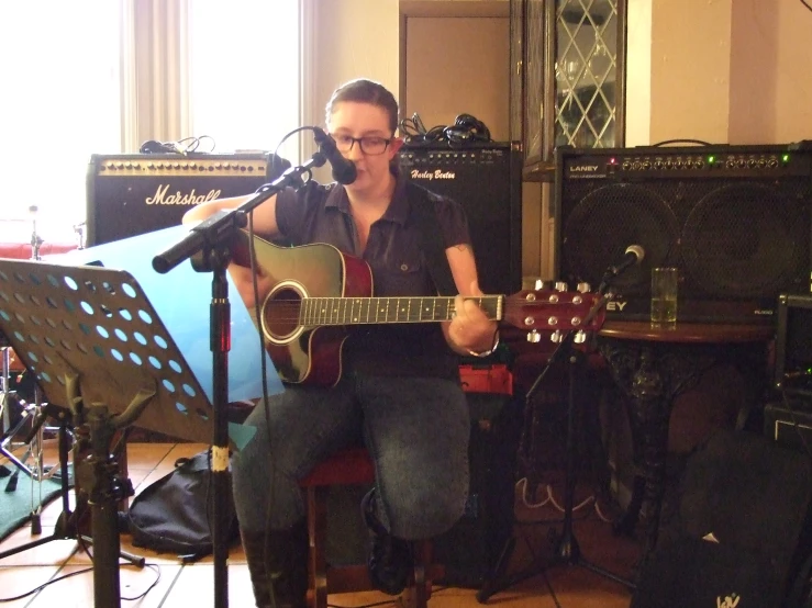 the man is playing the guitar in his recording studio