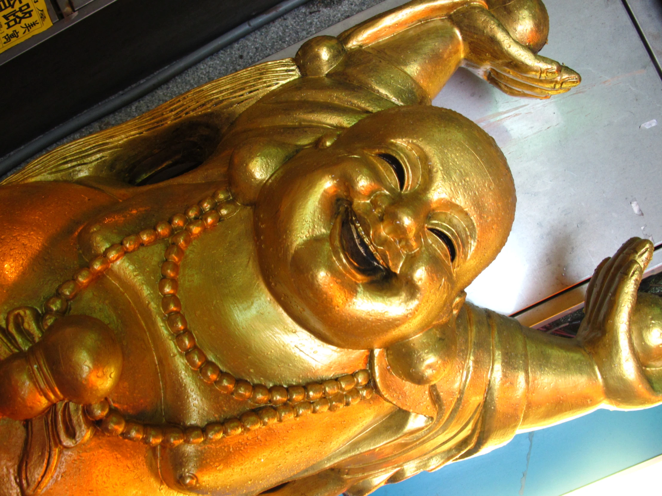 golden laughing buddha statue on display outside a store