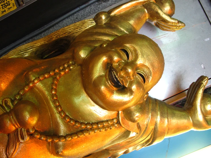 golden laughing buddha statue on display outside a store