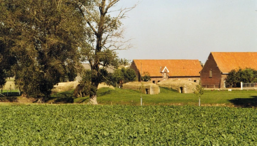 an old farmhouse and barn stands next to a field