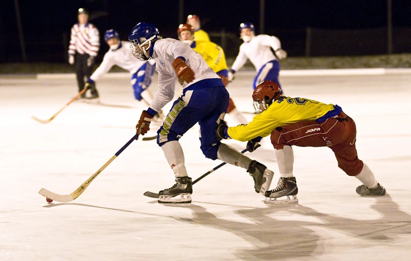 one player tries to steal the ball as another plays hockey