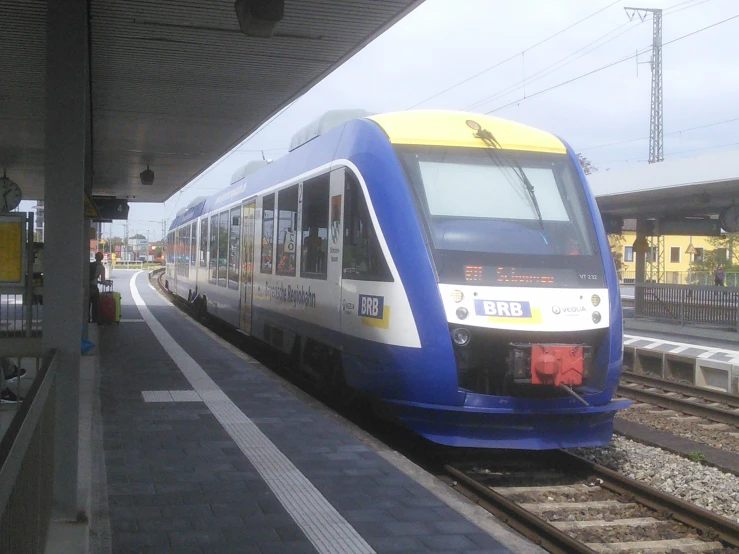 a blue and white train on tracks at a train station