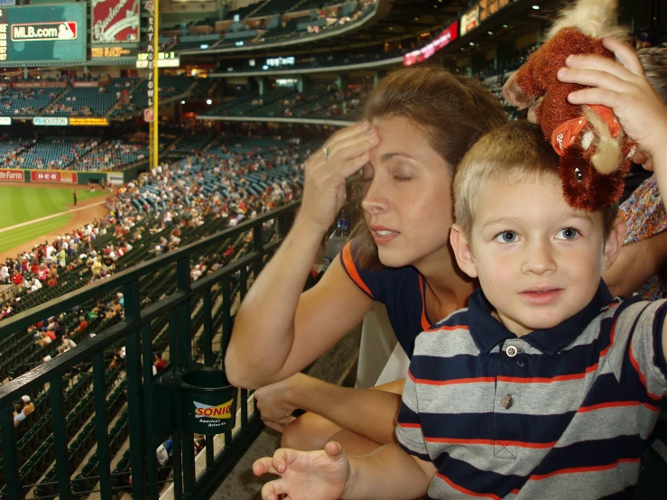 a family sits at a baseball stadium and watches from behind home plate