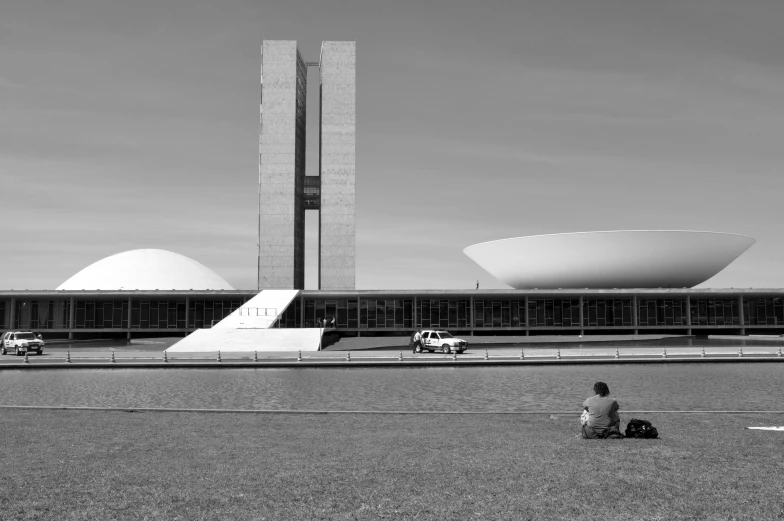 a man sitting in the grass next to a white building