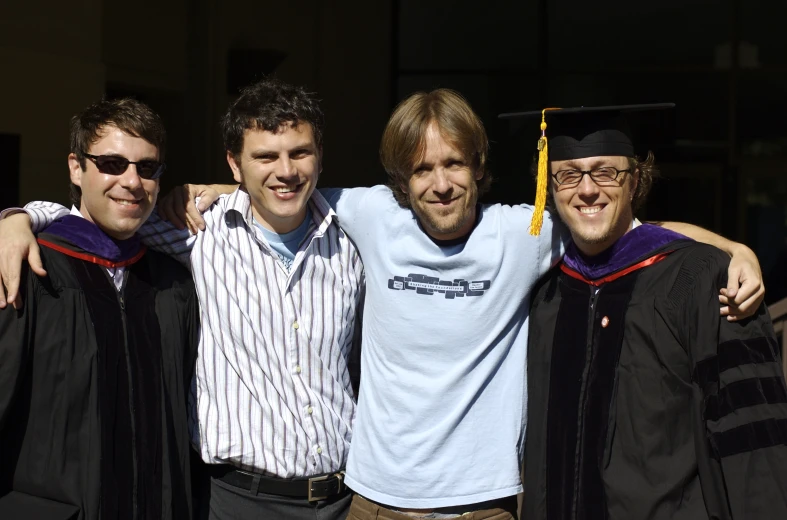 a few men in cap and gown are posing for a picture