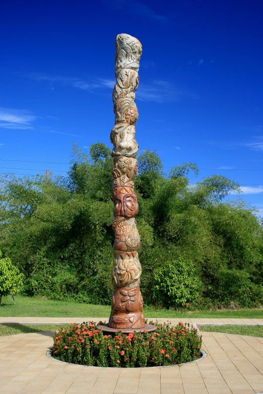 a tall stone sculpture surrounded by trees and flowers