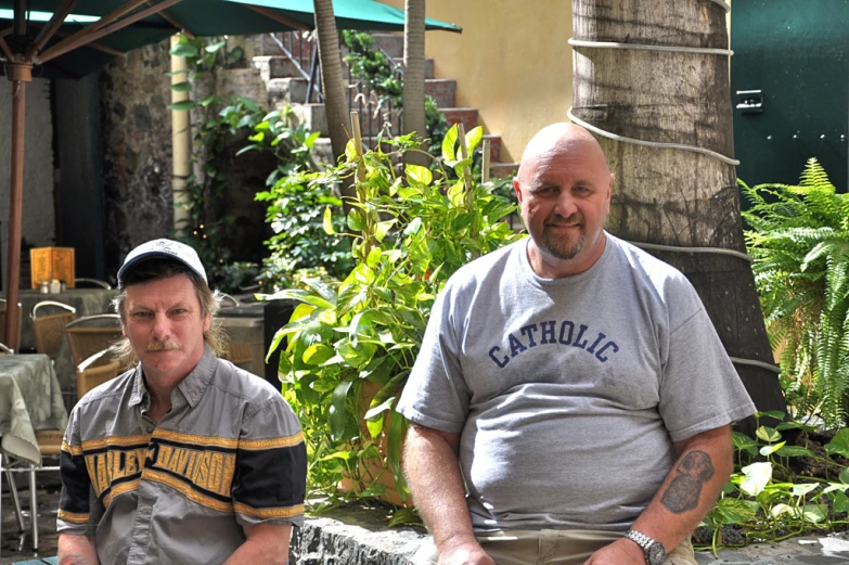 two men sitting down next to each other and smiling