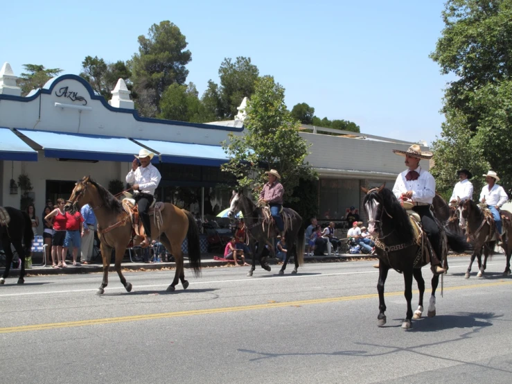 people are riding horses in front of businesses