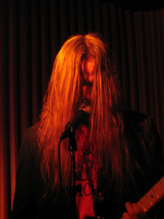 a man holding a guitar while standing in front of a microphone