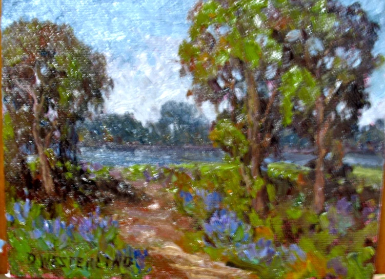 some trees and blue flowers near some water