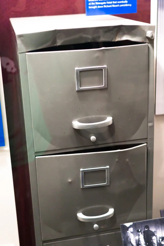 three file cabinets on display with an old time po in front