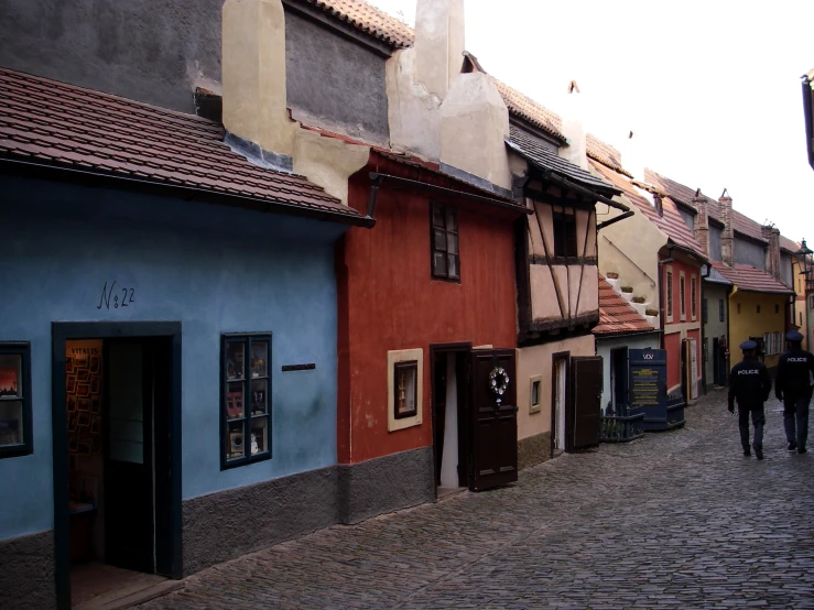 people are walking down a cobblestone street lined with buildings