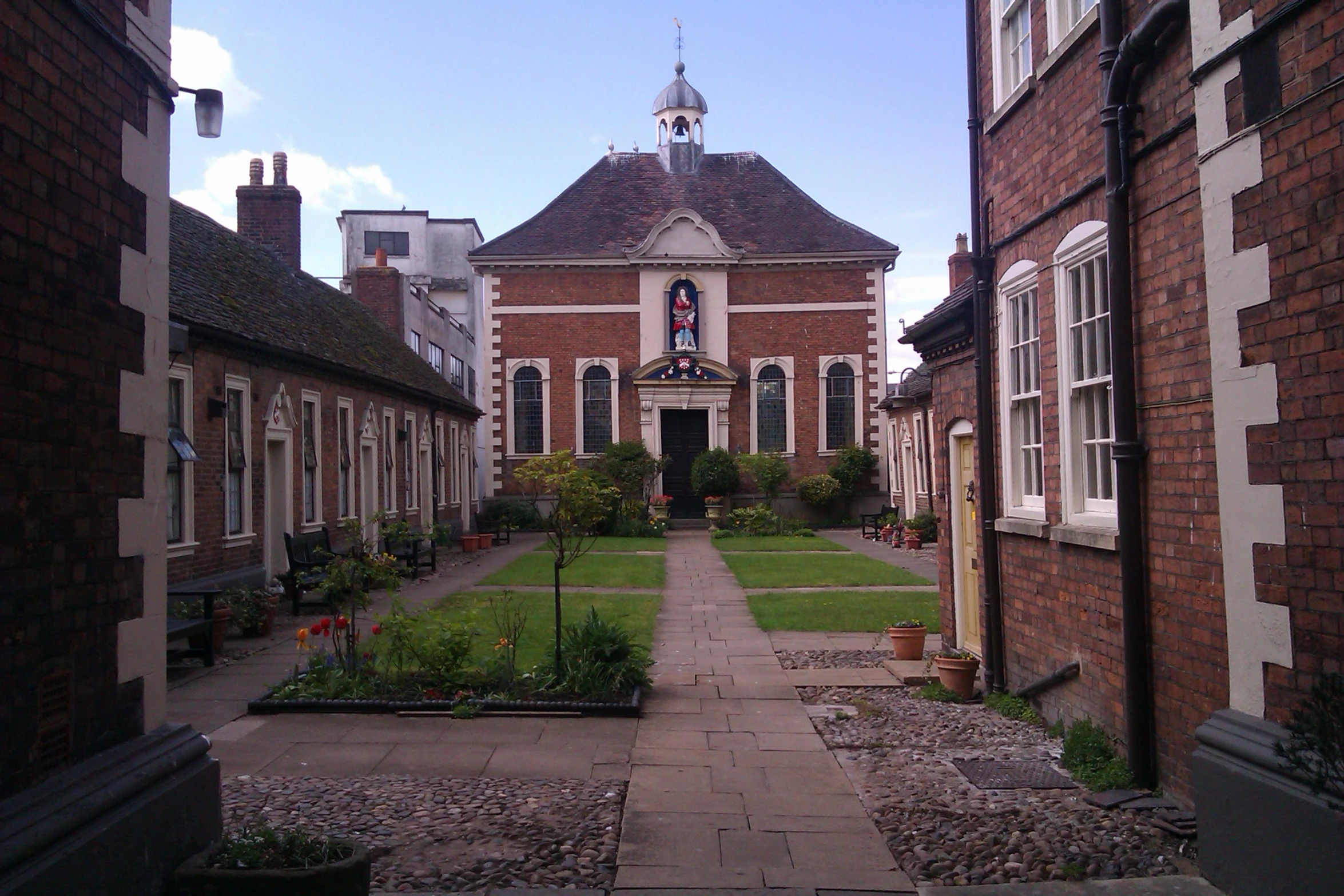 an alley with houses, flowers and a garden