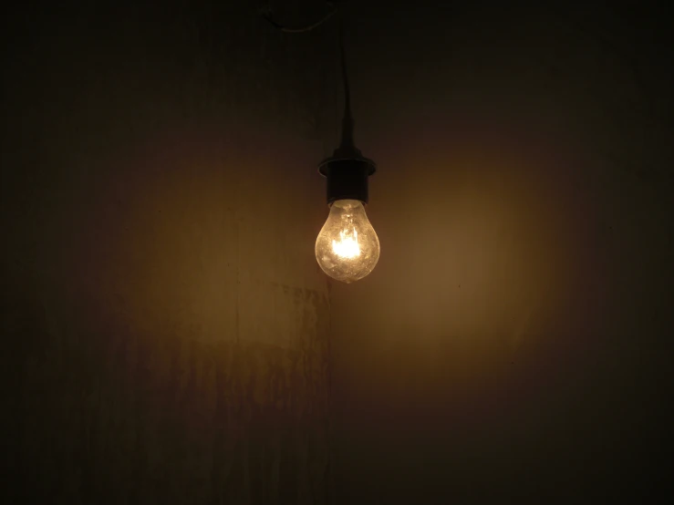 a light bulb hanging from a wire near a wall