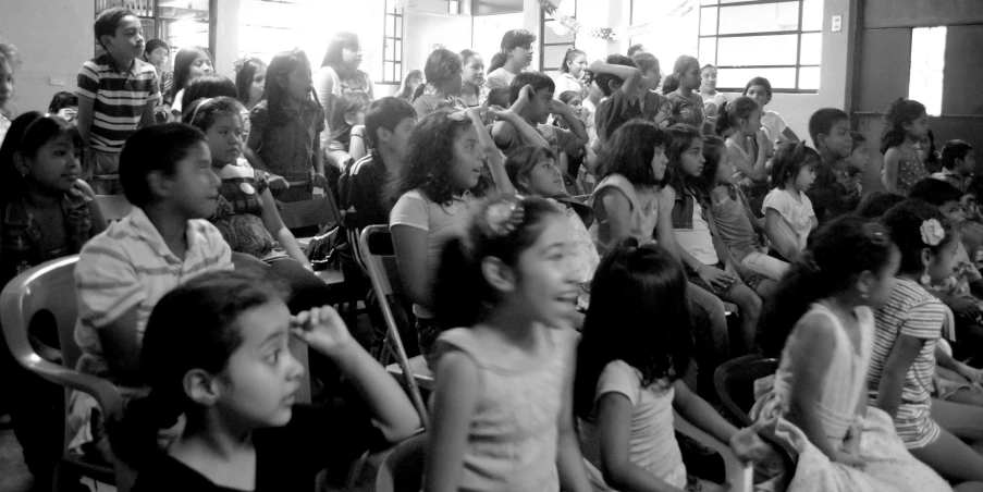 a group of people sitting in front of a crowd of children