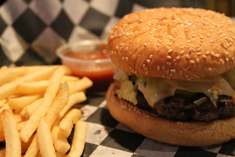 the burger with french fries is sitting on a checkered cloth