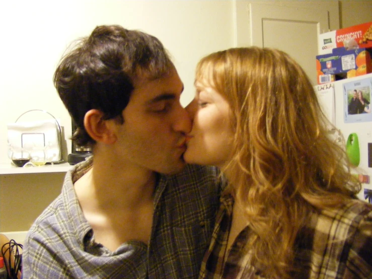 a man kissing a woman in front of a kitchen counter