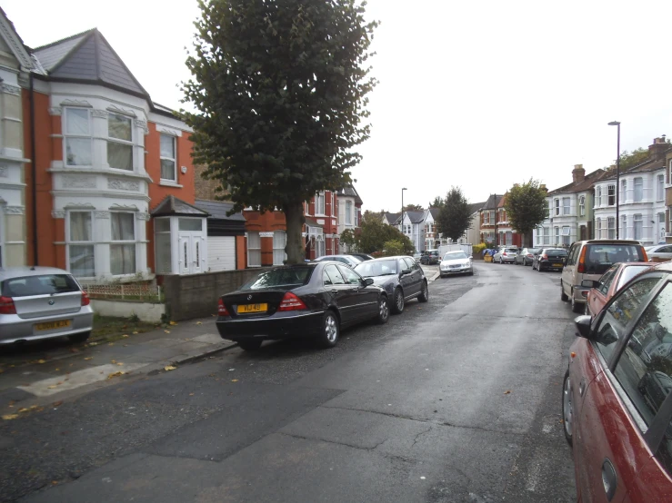 several cars are parked on the street by some tall buildings