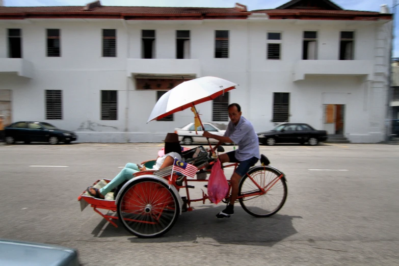 a man riding on the back of a bike with an umbrella