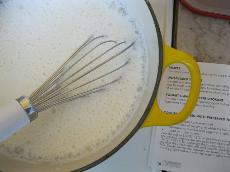 a whisk in a pot filled with flour on top of a table