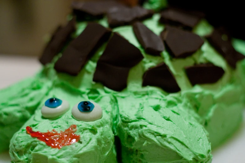 there is a green cake with googly eyes