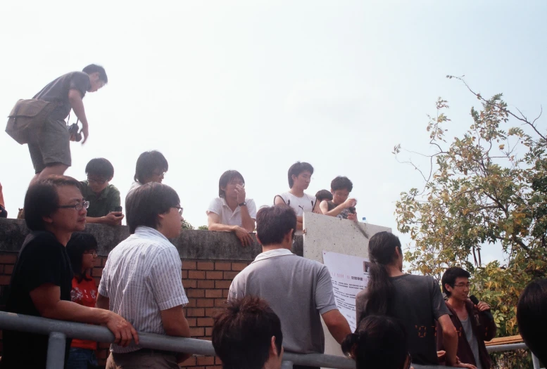 a crowd of people on a roof top with a sign attached to the side