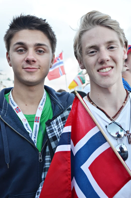 two young men who are standing together holding a flag